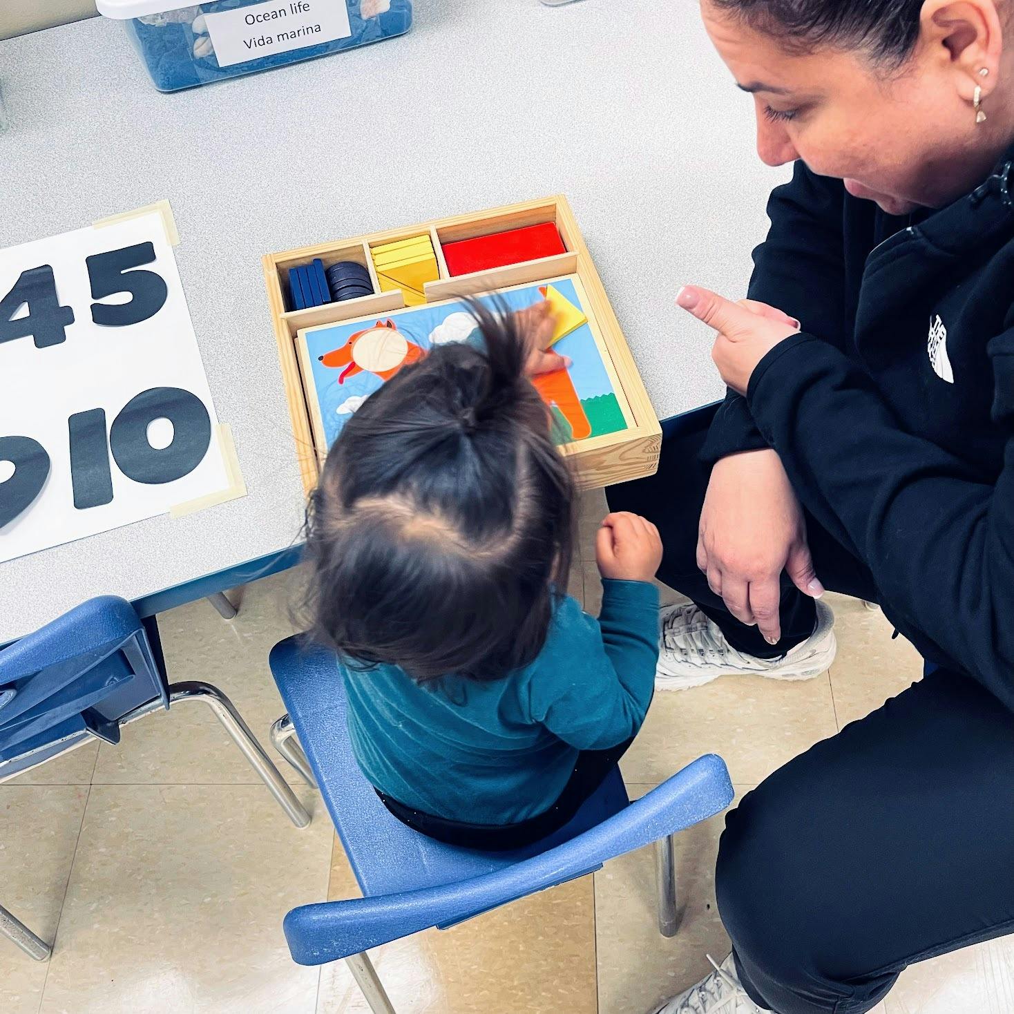 Adult and child playing with a wooden puzzle at a table