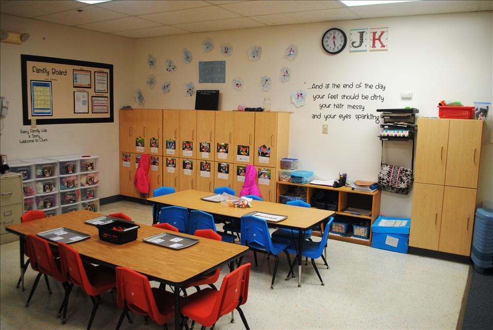 Classroom with tables and chairs, wall art, and storage cabinets