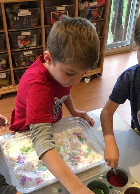 Child playing with sensory bin with colorful items
