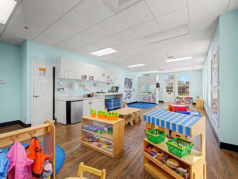 An empty classroom with child-sized furniture and light blue walls
