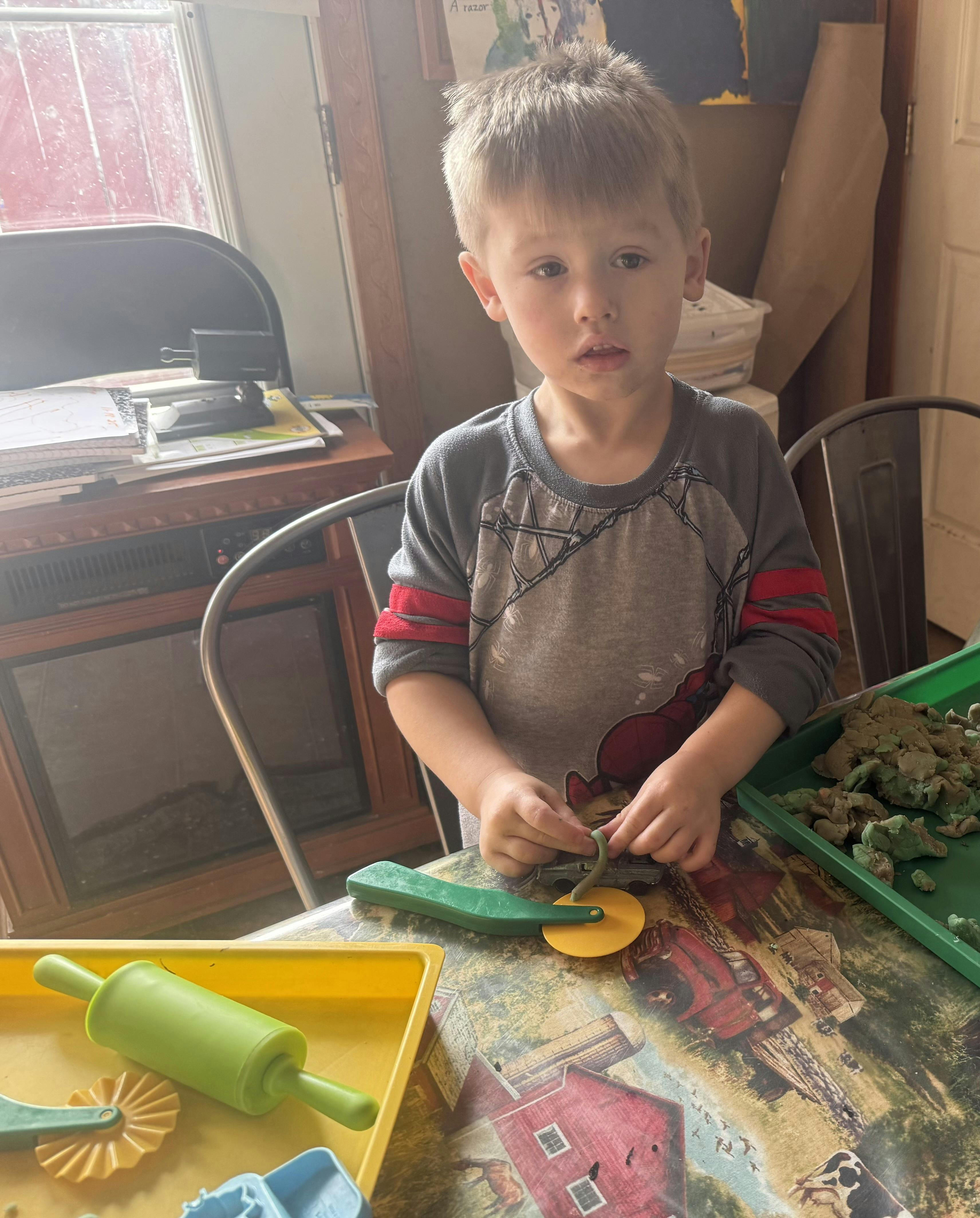 Child playing with modeling clay and tools at a table