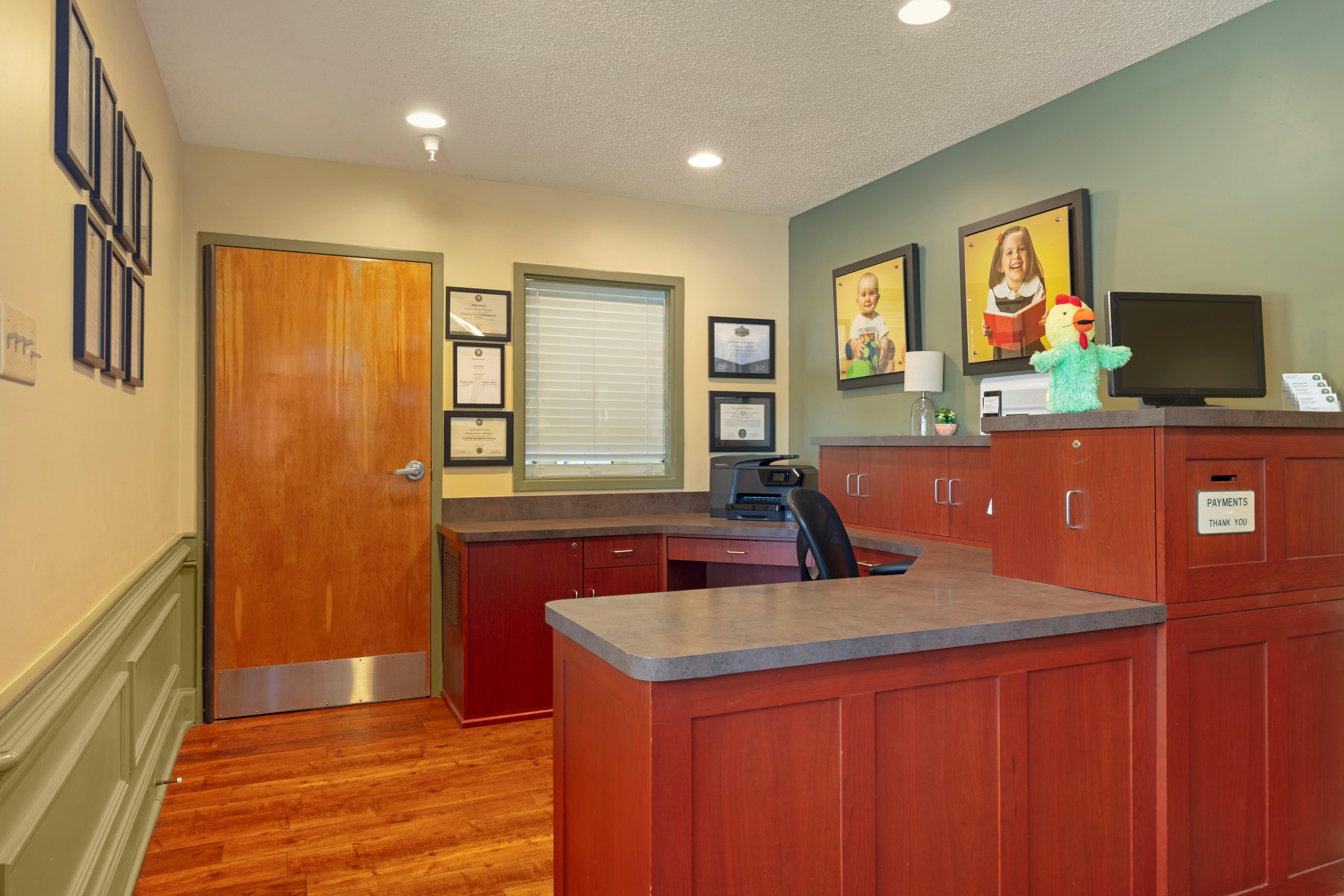 Reception desk with wood cabinetry, window with blinds, and framed photos