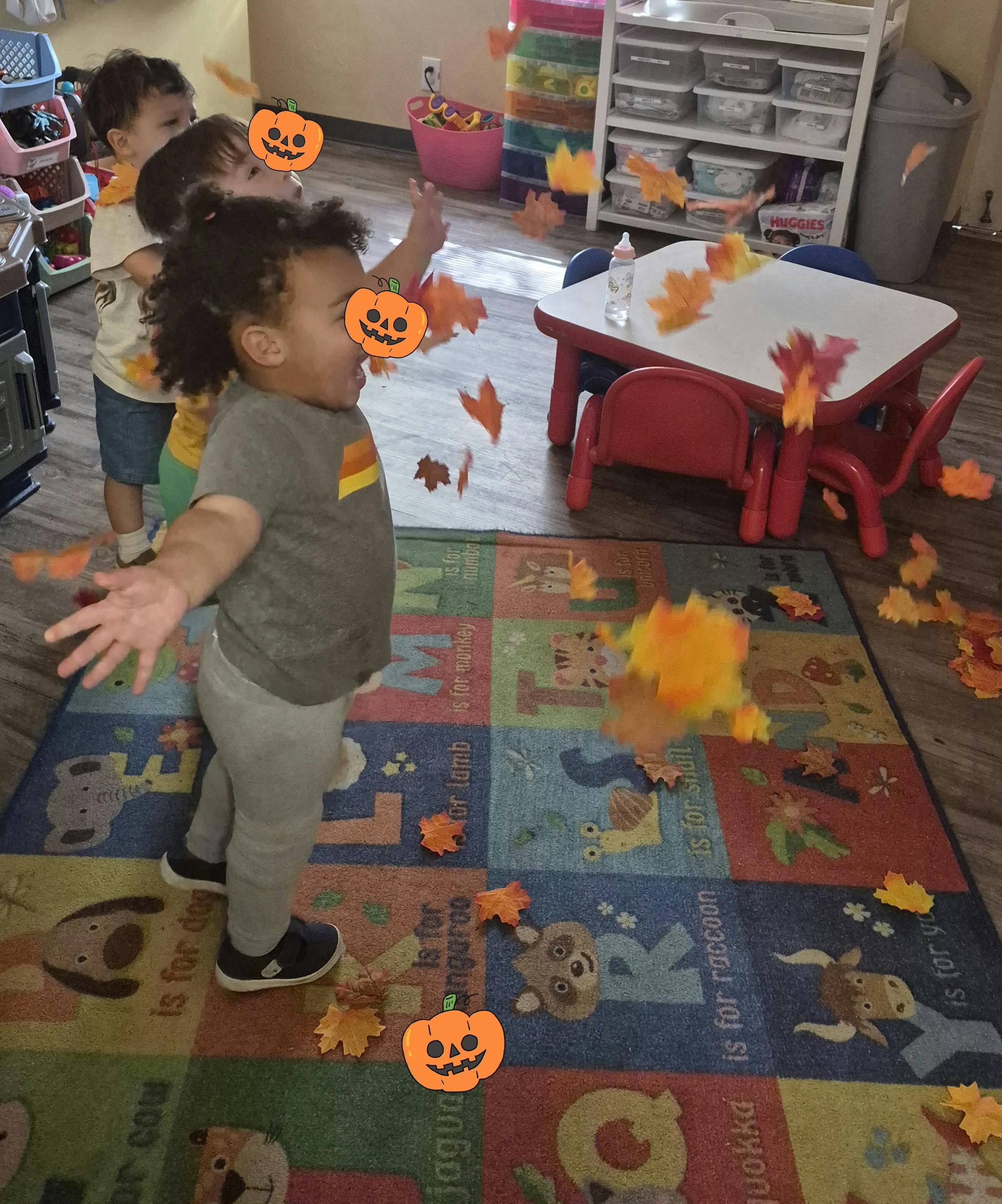 Children playing with falling faux autumn leaves in a classroom