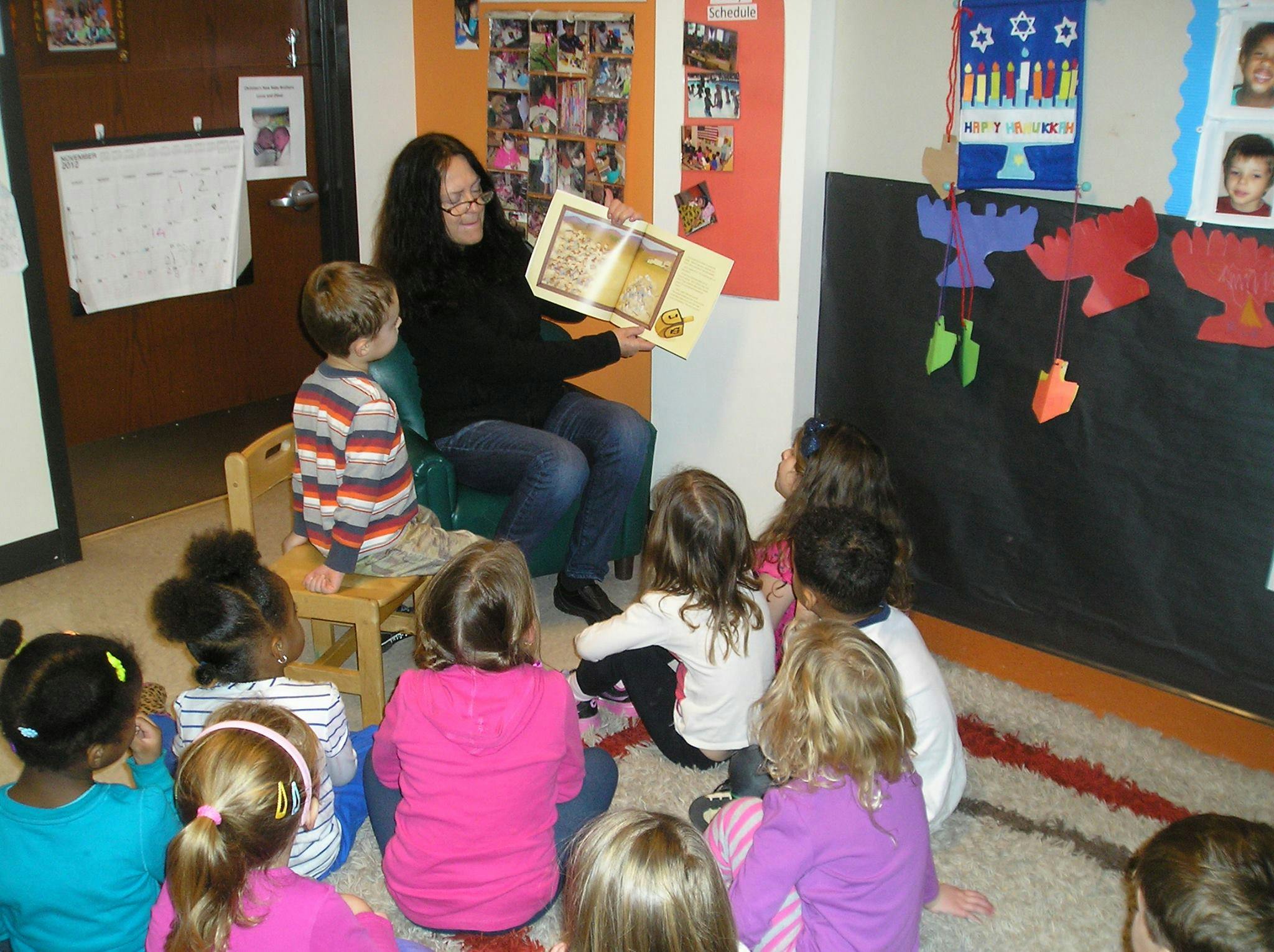 Person reading a book to a group of children in a classroom