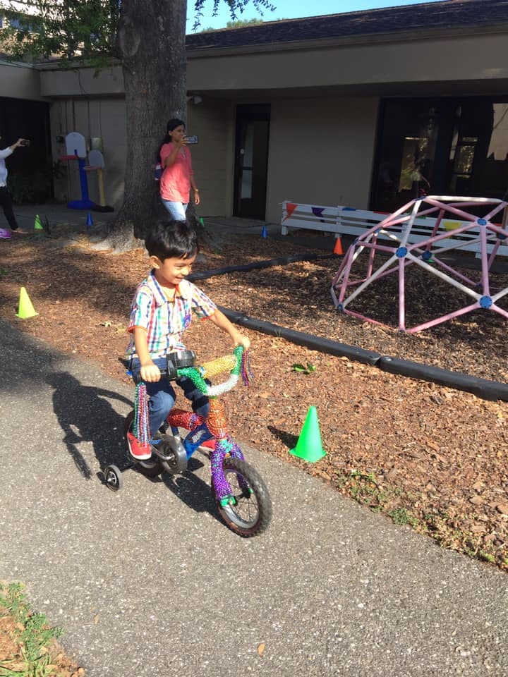 Child riding a bicycle with training wheels on a paved path