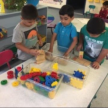Three children playing with building blocks and colorful interlocking toys