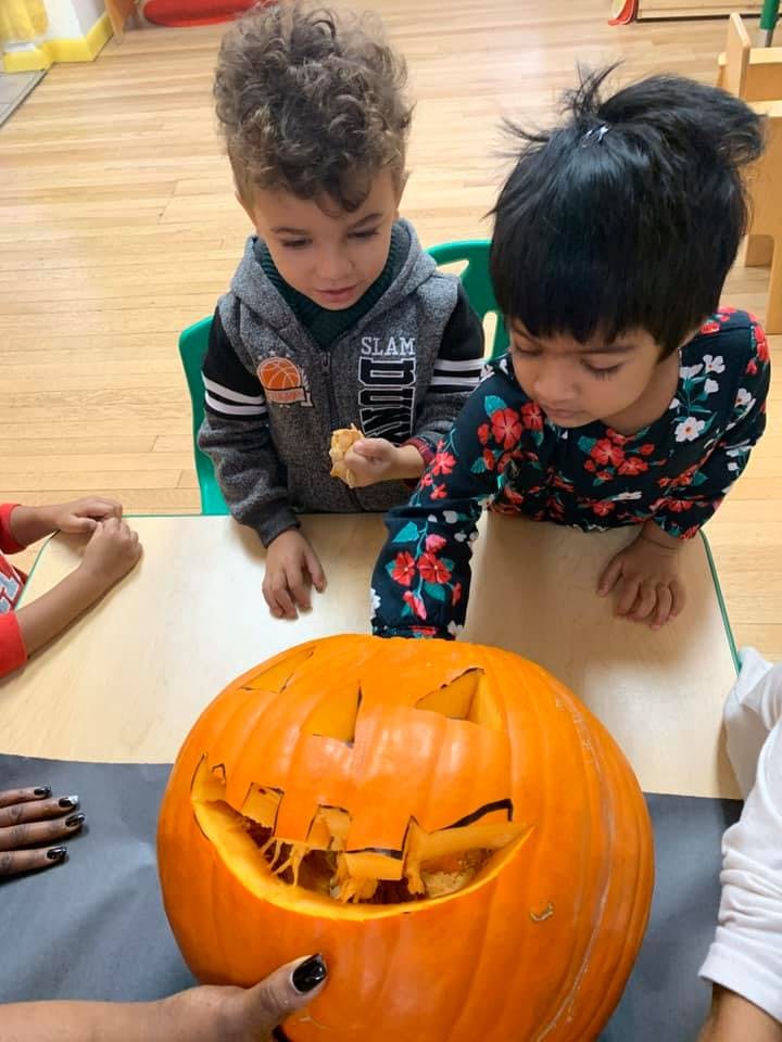 Two children looking at a carved pumpkin on a table