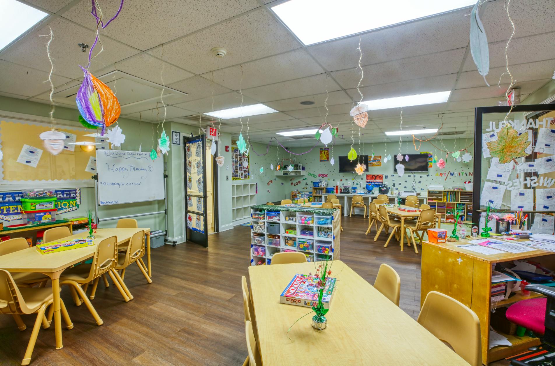 Colorful classroom with small tables and chairs, decorated with ceiling hangings