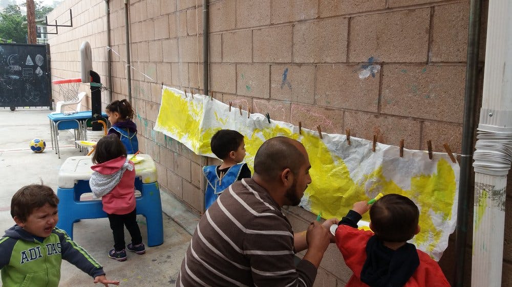 Adult and children painting on fabric hanging on a wall