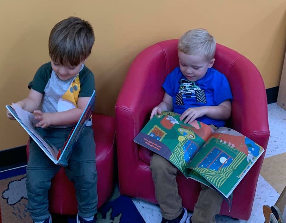 Two children reading books in a classroom