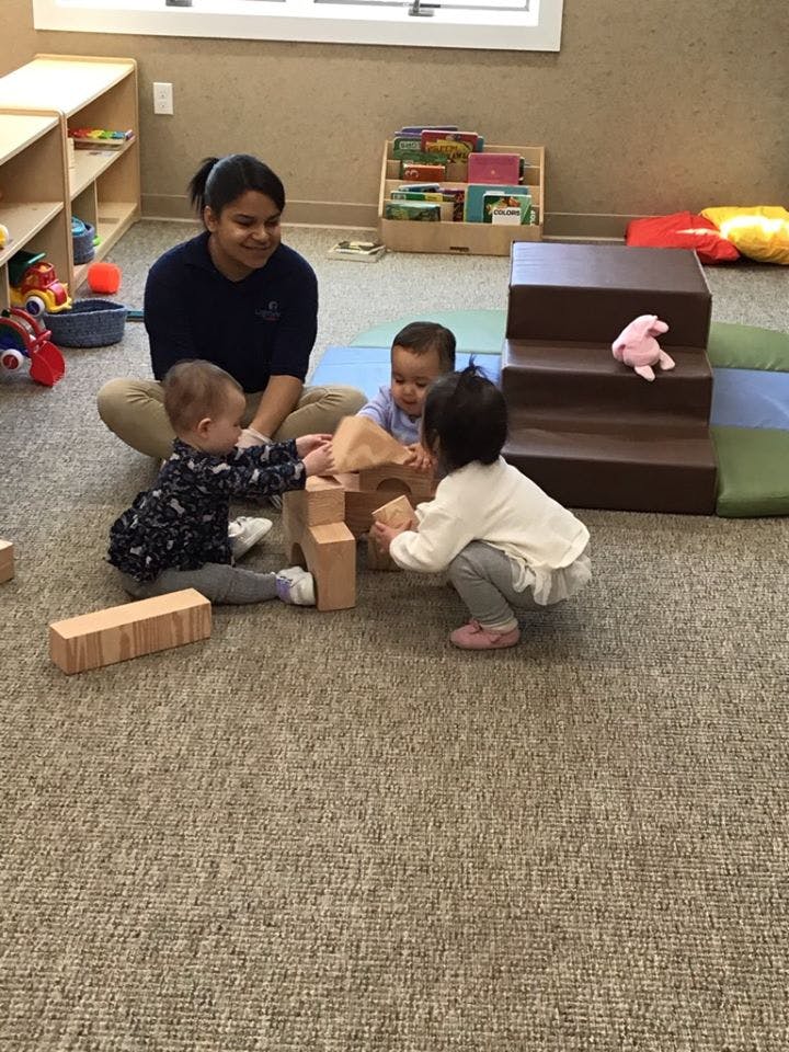 Adult and three children playing with wooden blocks on the floor