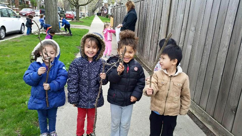 Four children holding sticks on a sidewalk