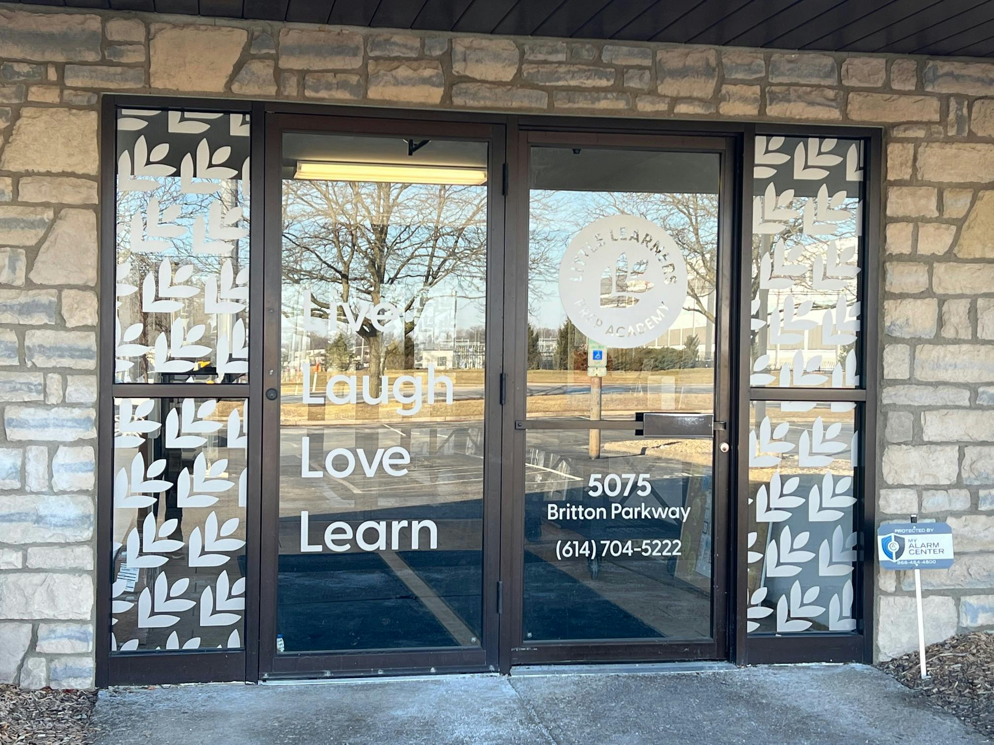 Glass doors with text "Live Laugh Love Learn" and address