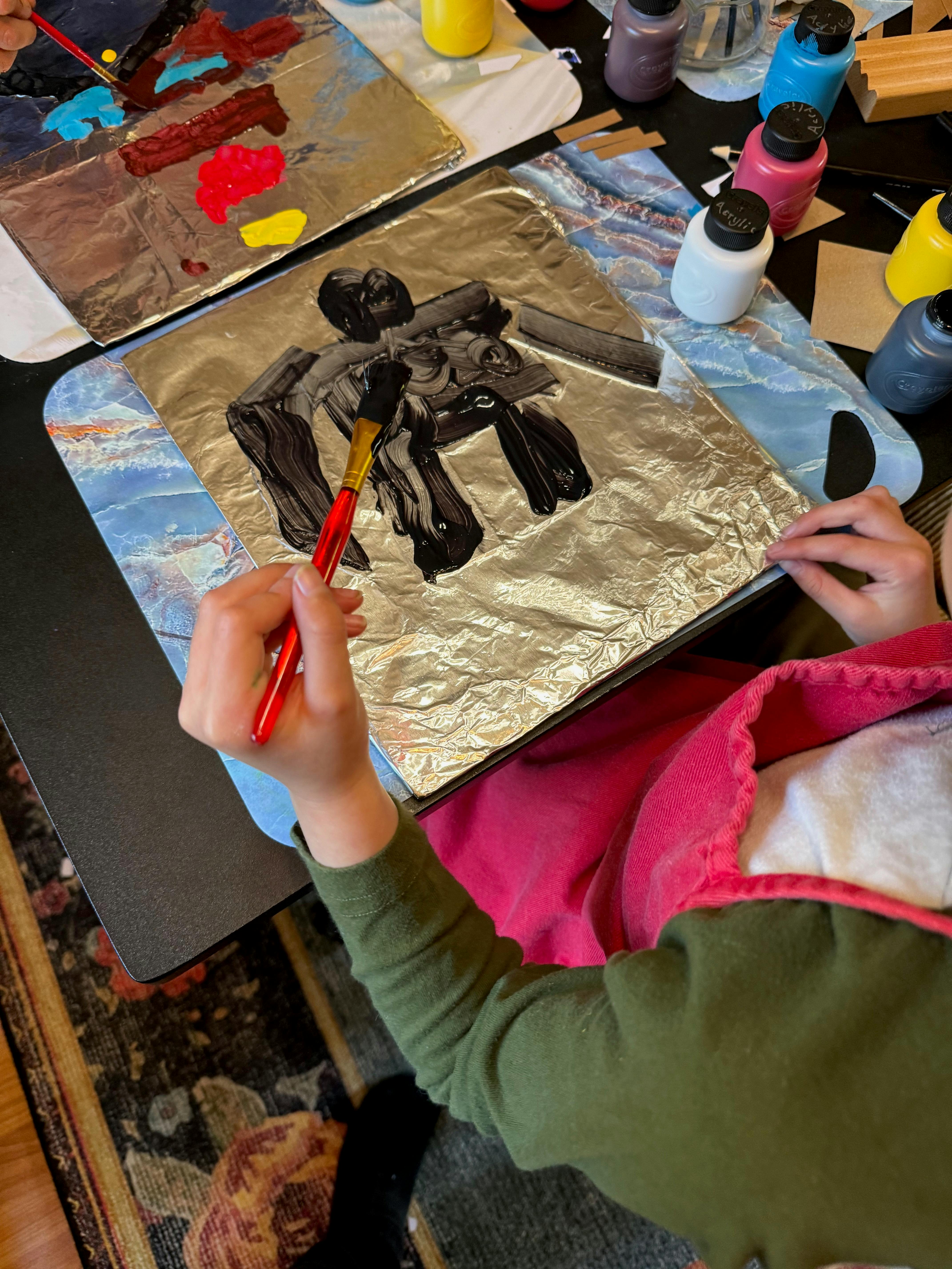 Child painting on foil with a brush