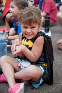 Child in a Batman costume sitting on the ground