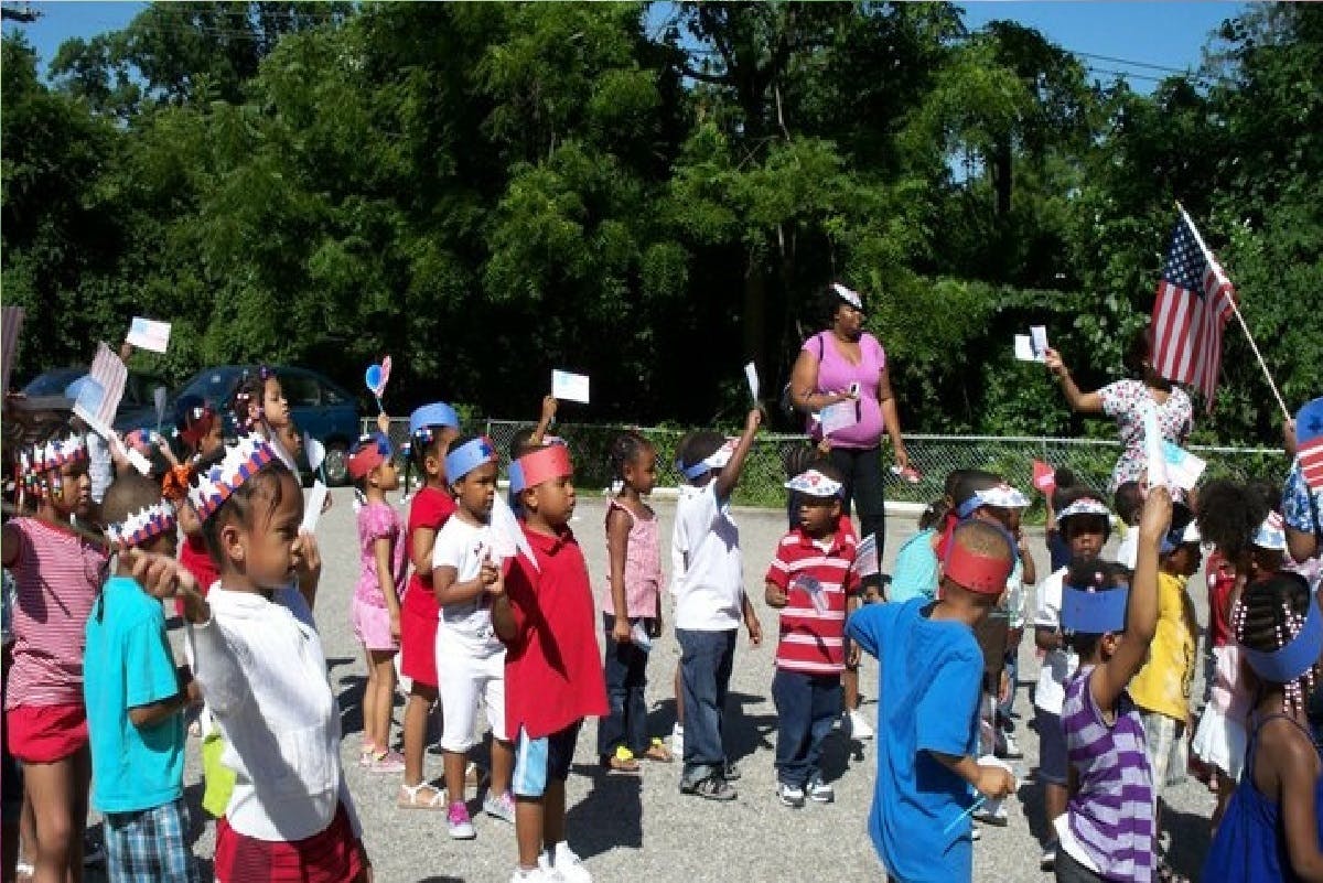 Children and adults holding small flags outdoors