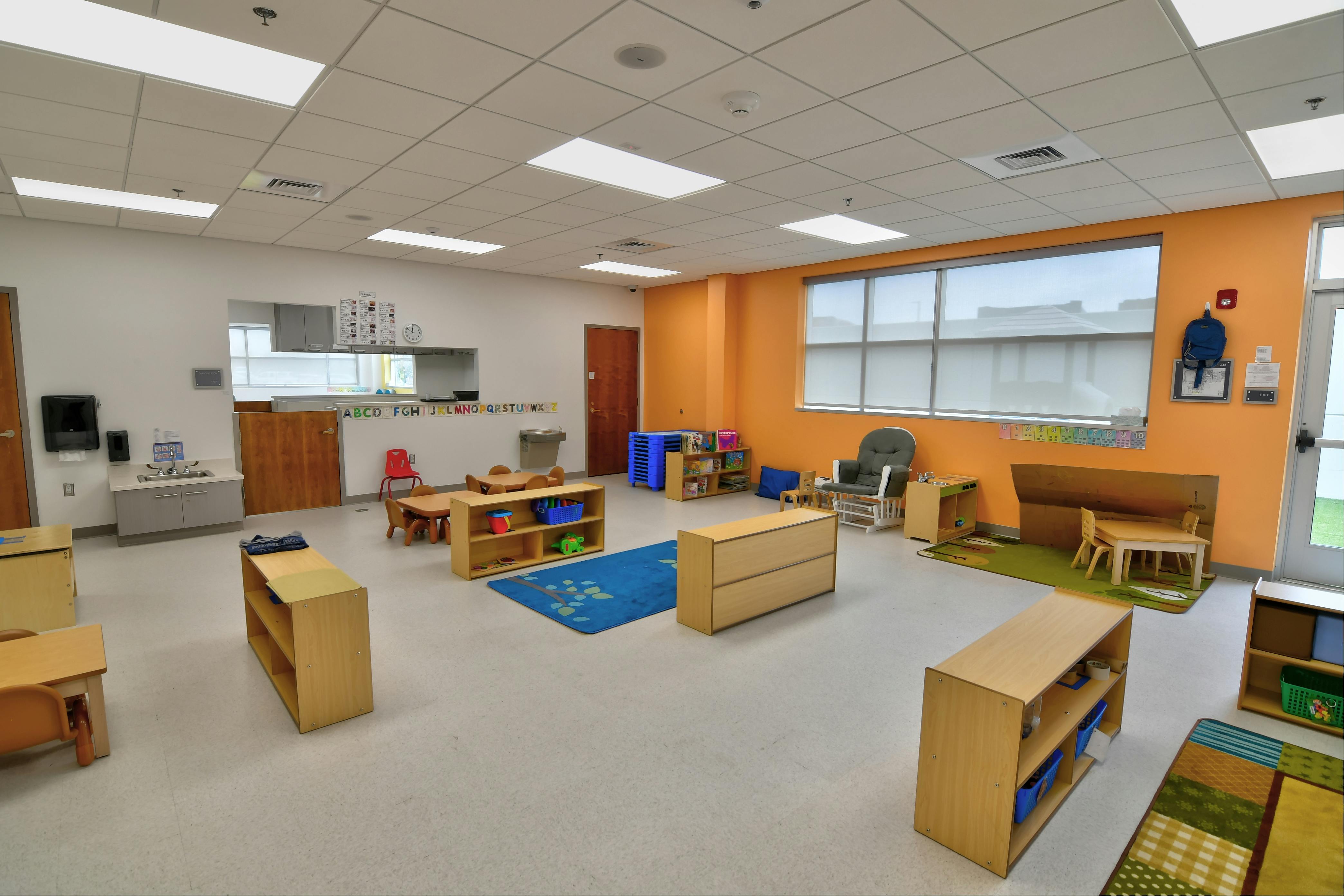 Empty classroom with small wooden furniture and colorful rugs