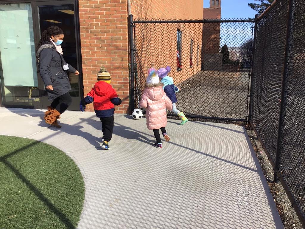 Person and children playing with a soccer ball outdoors