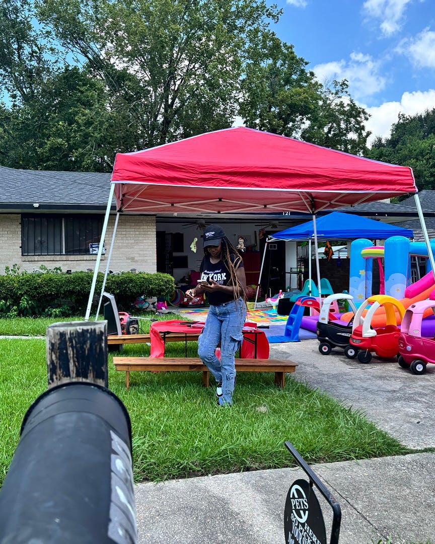 Person standing under a red canopy tent with children's toys nearby