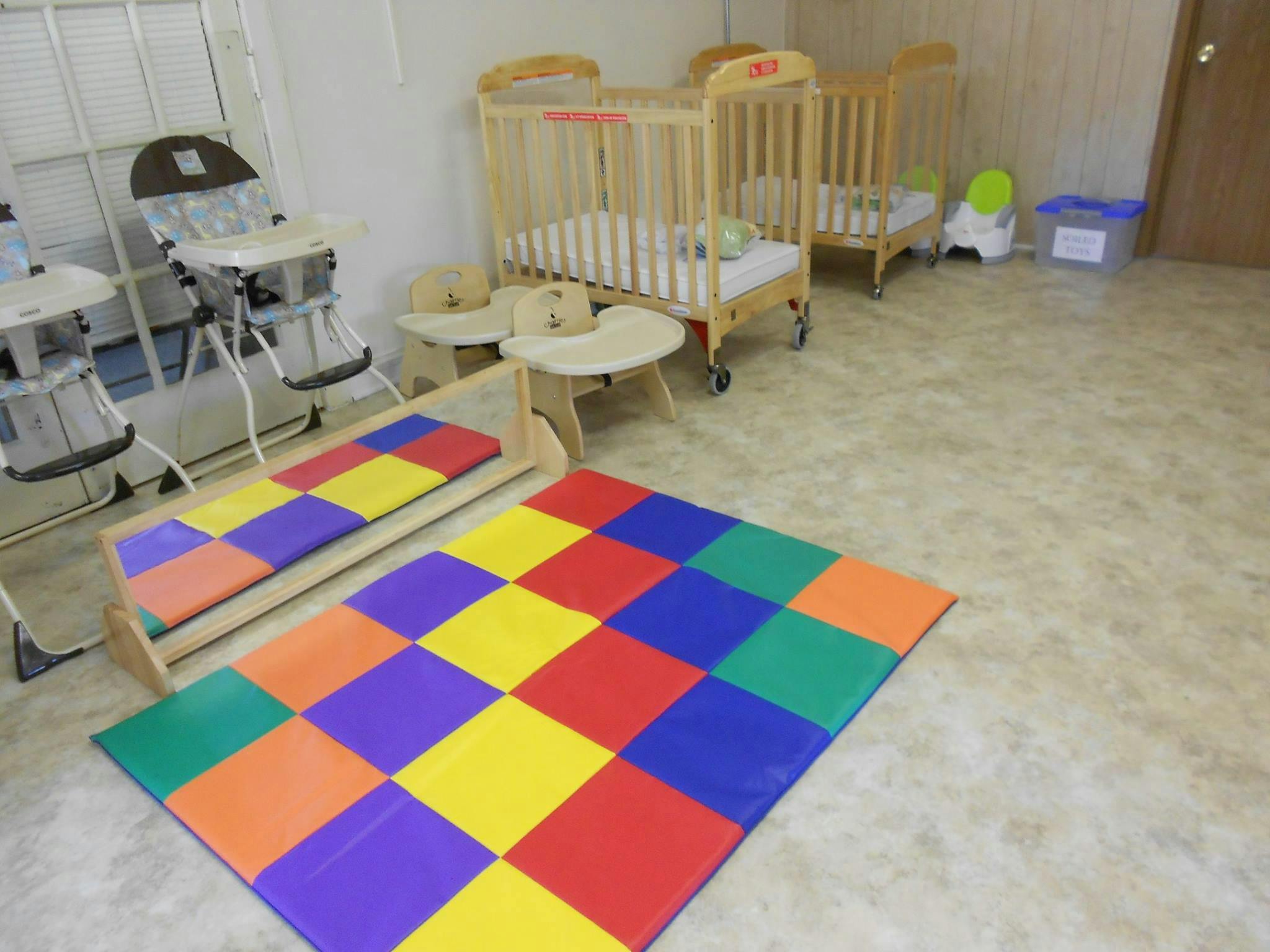Playroom with cribs, high chairs, and colorful play mats