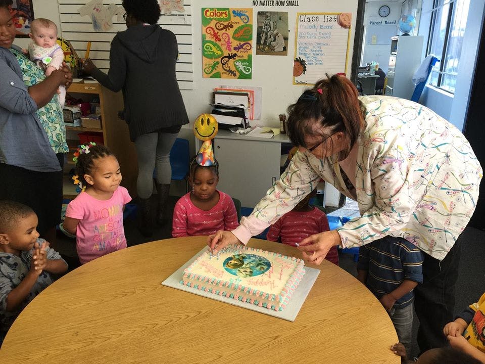 Adult serving cake to children at a table