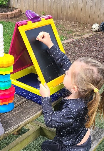 Child drawing on a chalkboard easel outdoors