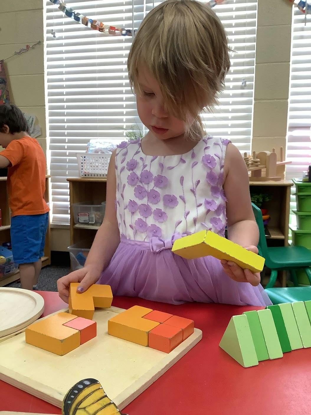 Child playing with wooden blocks at a table in a classroom
