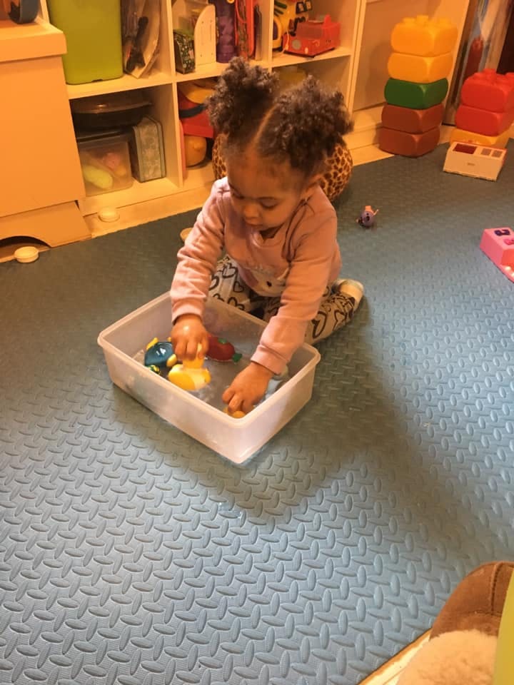 Child playing with toys in a container of water