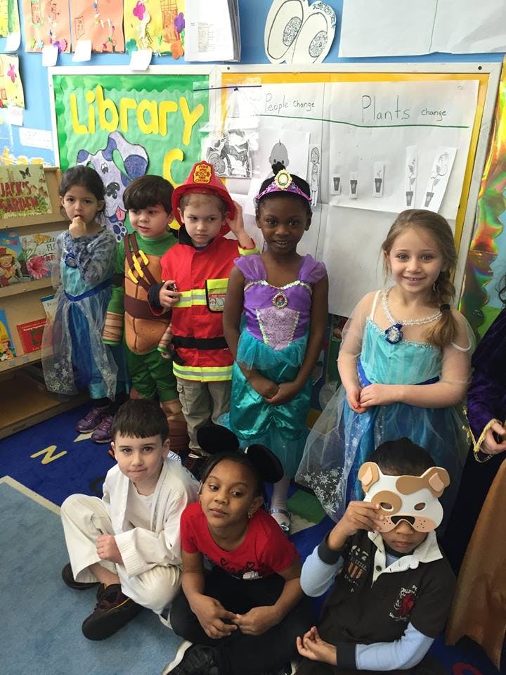 Children in costumes standing and sitting in a classroom