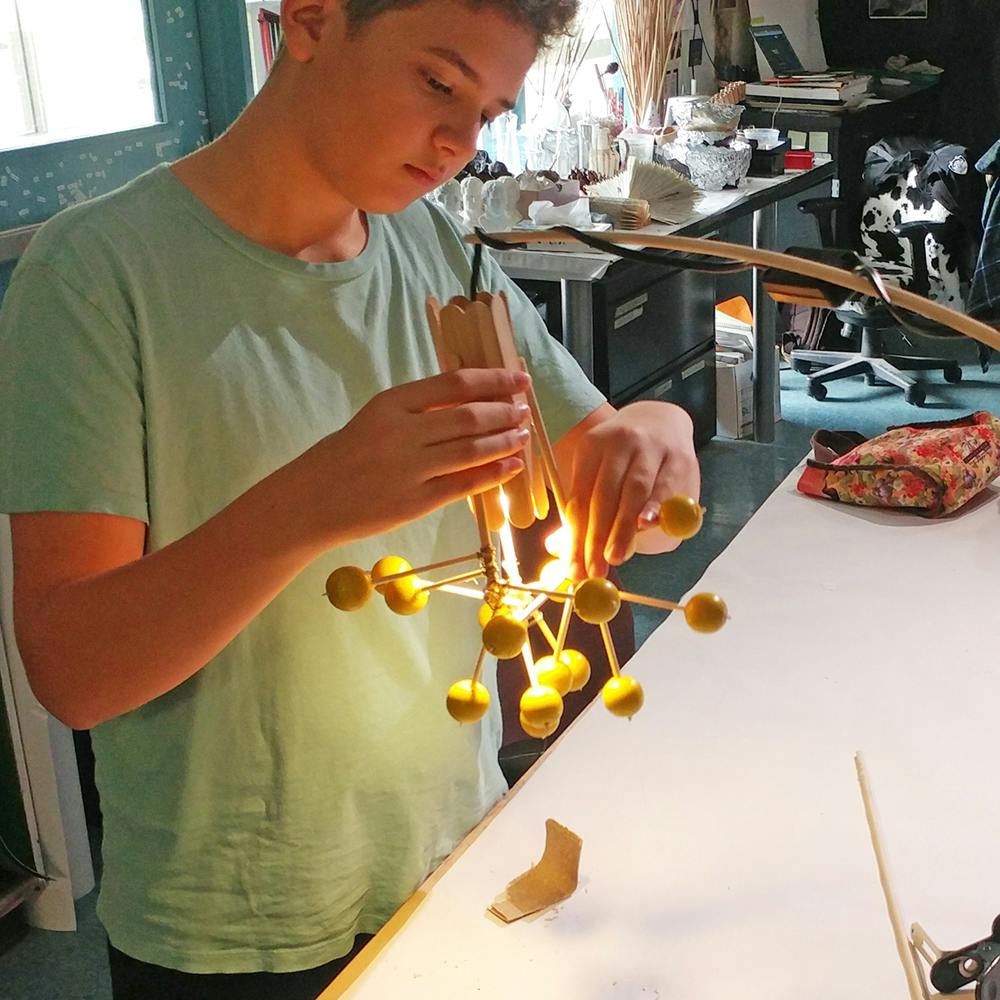 Child building a model with sticks and yellow spheres