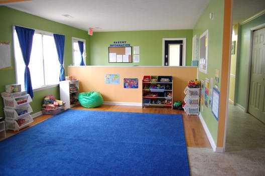 Playroom with blue rug, green walls, and storage shelves