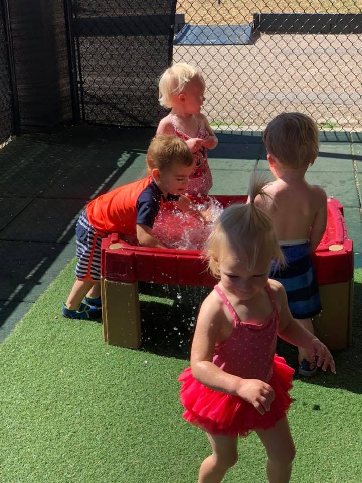 Children playing with water in a red table