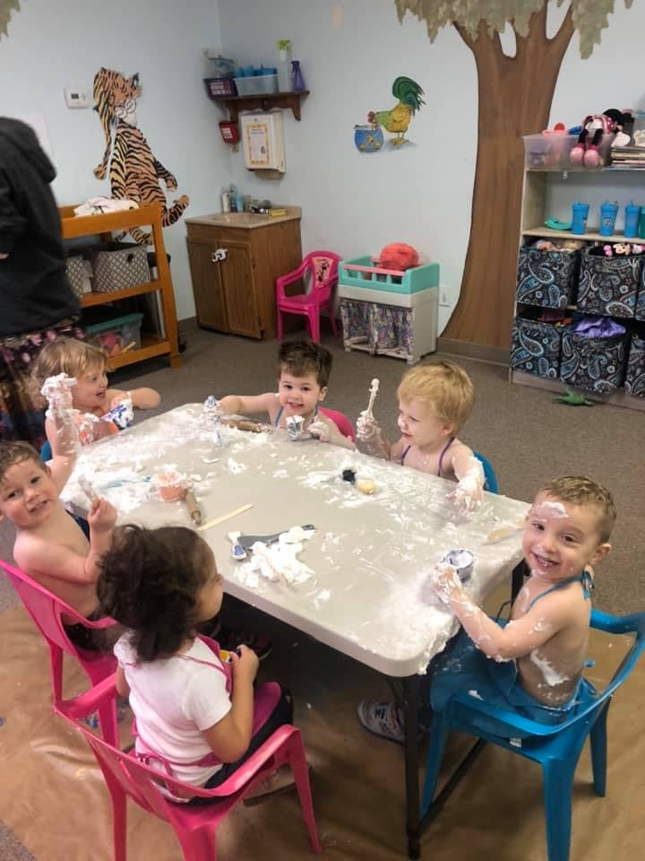 Children playing with shaving cream at a table in a classroom