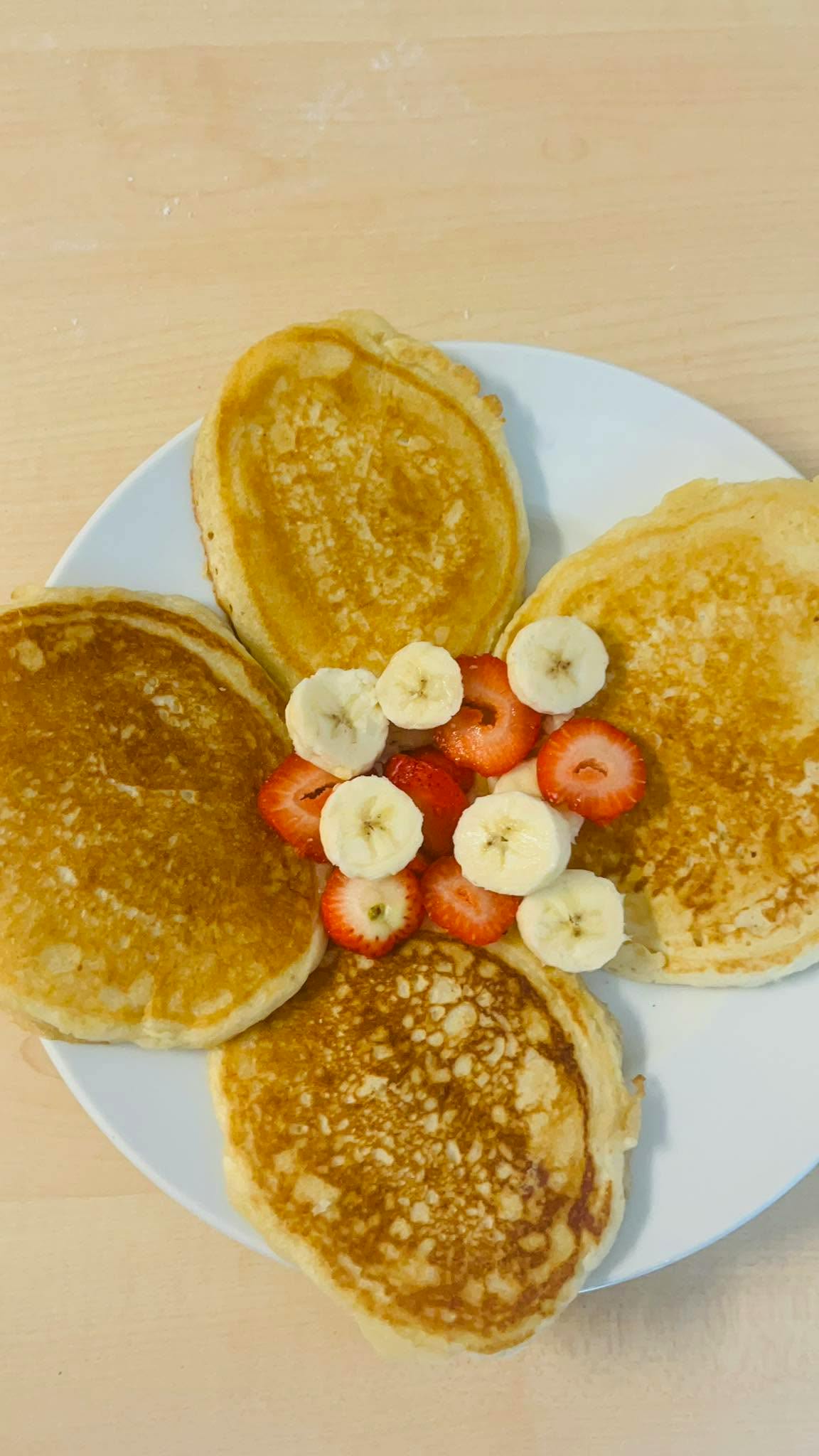Pancakes topped with sliced strawberries and bananas on a plate