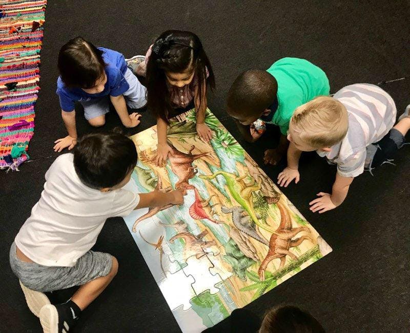 Children on floor assembling a large puzzle