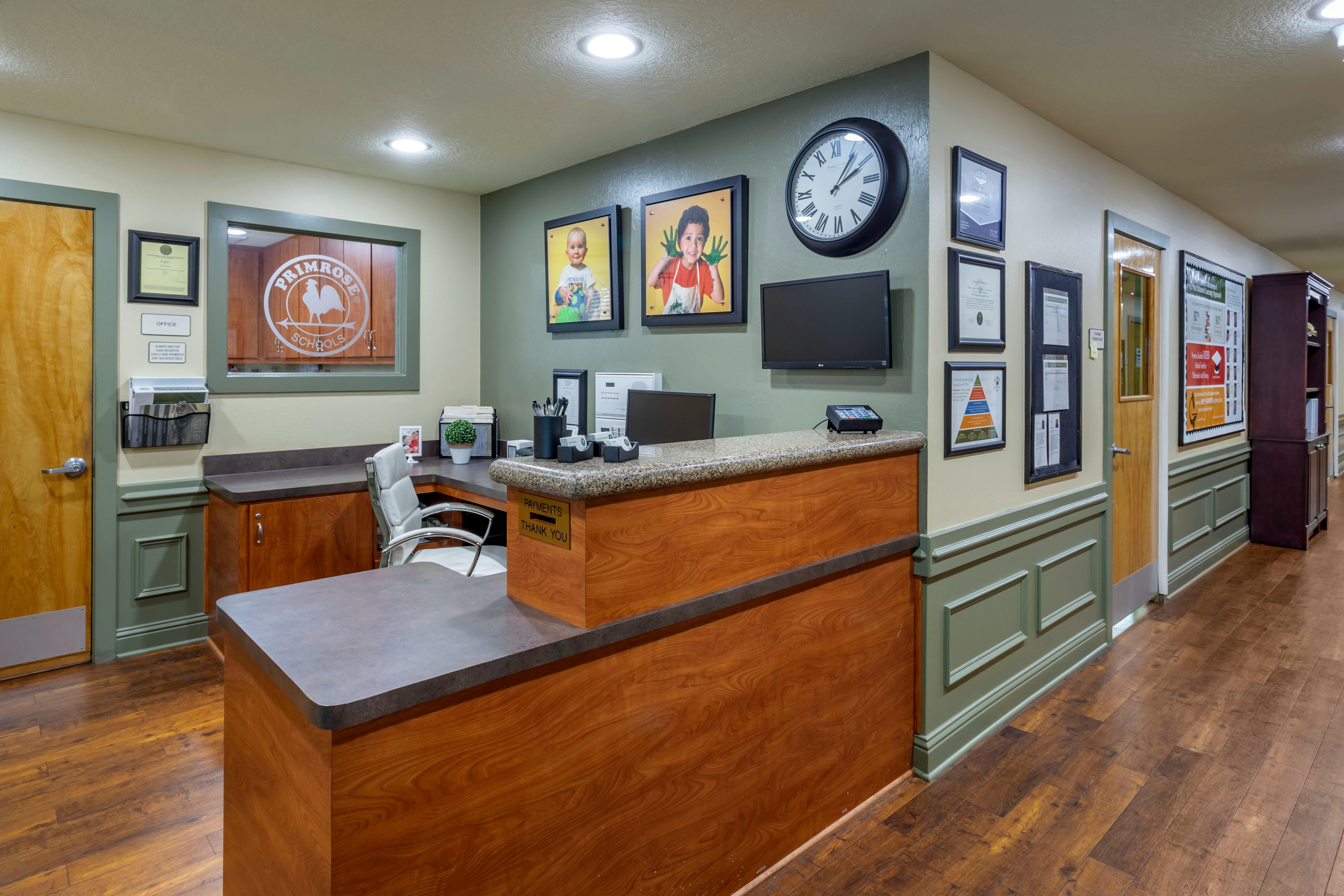 Reception area with a wooden desk, office window, and hallway
