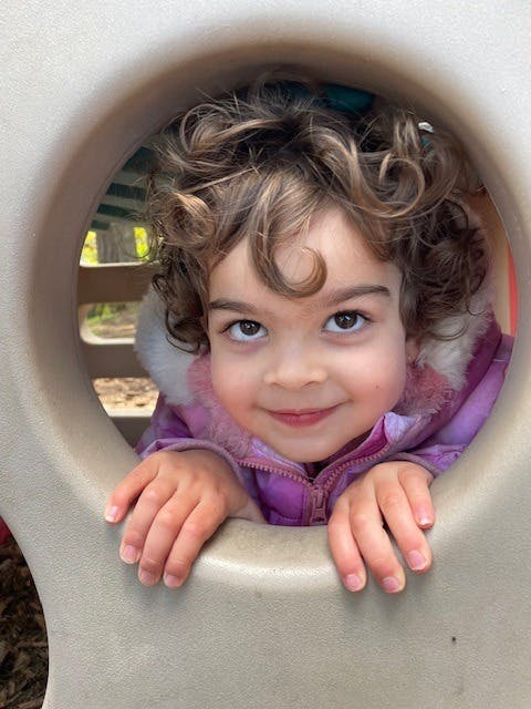 Child looking through a round opening on a playground structure