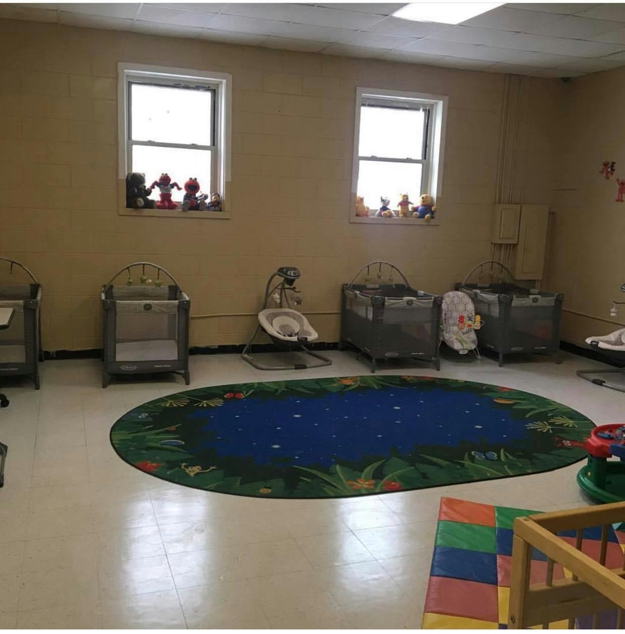 Nursery room with multiple cribs, a baby bouncer, and a blue rug