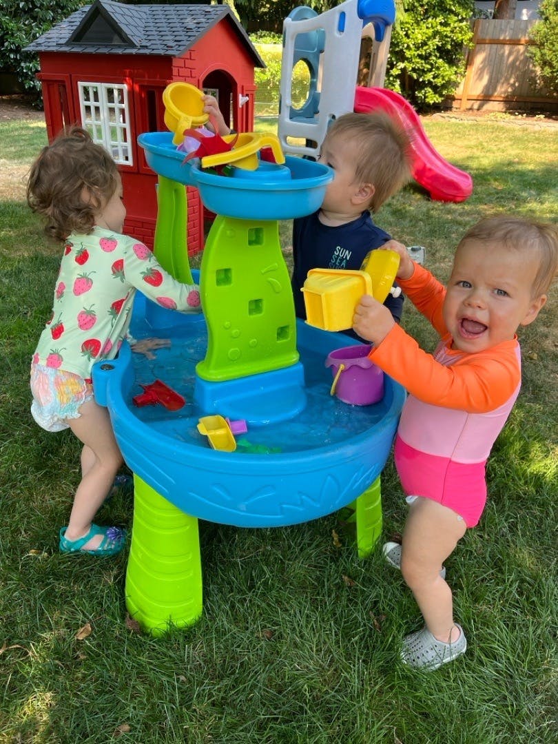 Three children playing at a water table outdoors