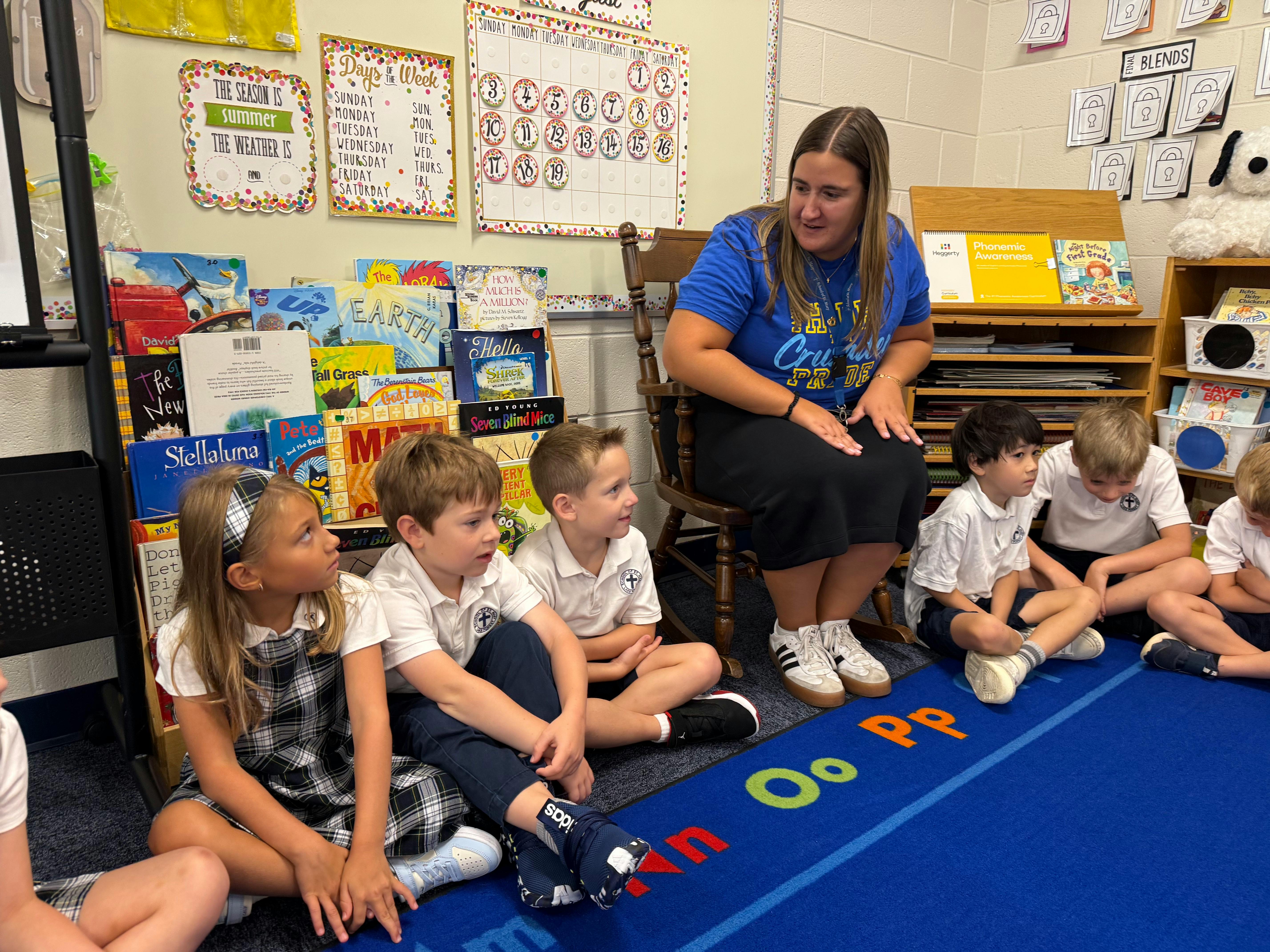 Teacher and five children sitting on a rug in a classroom