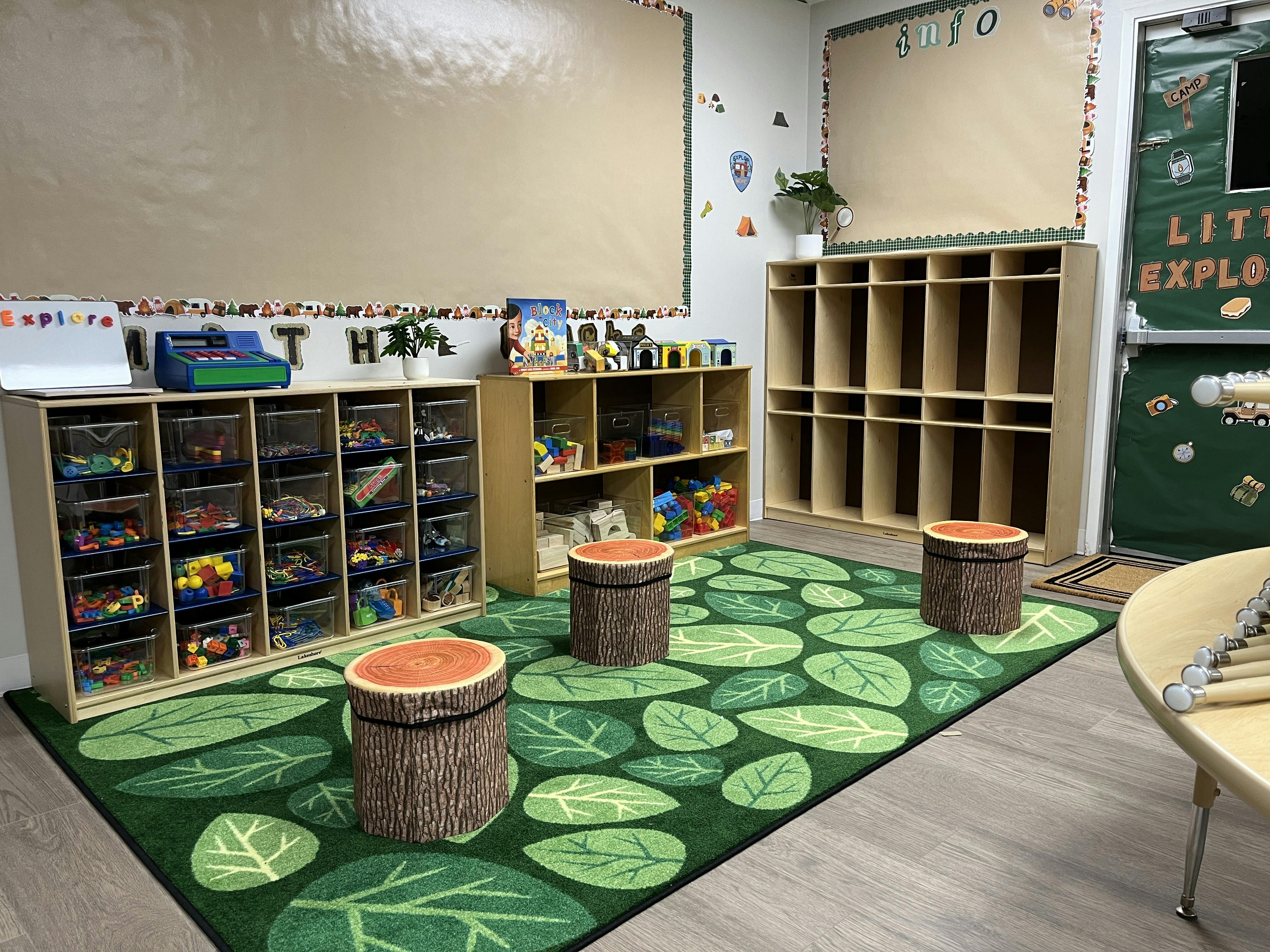 Classroom interior with wooden toy shelves and stump stools on a leaf rug