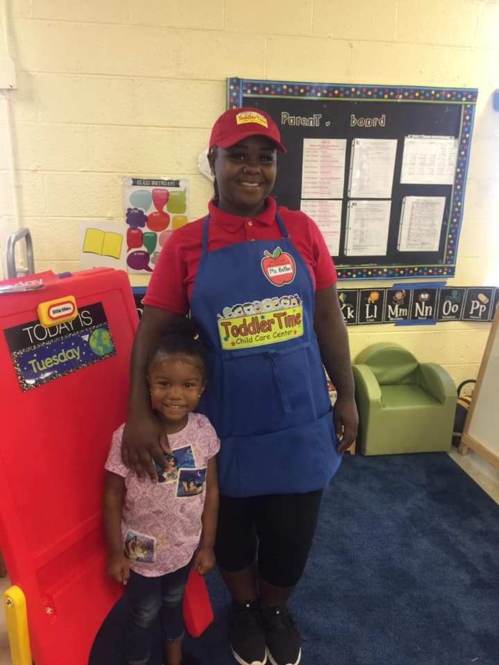Person in an apron with a child in a classroom