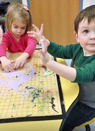 Two children finger painting at a table