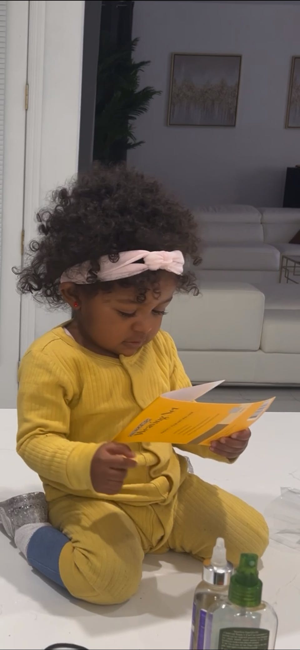 Child in yellow clothing reading a card