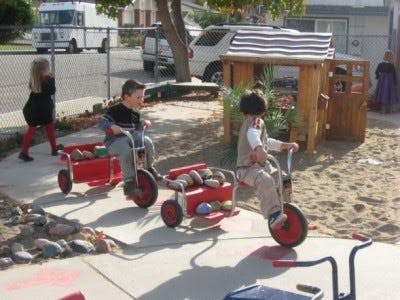 Children playing with wagons and tricycles on a playground