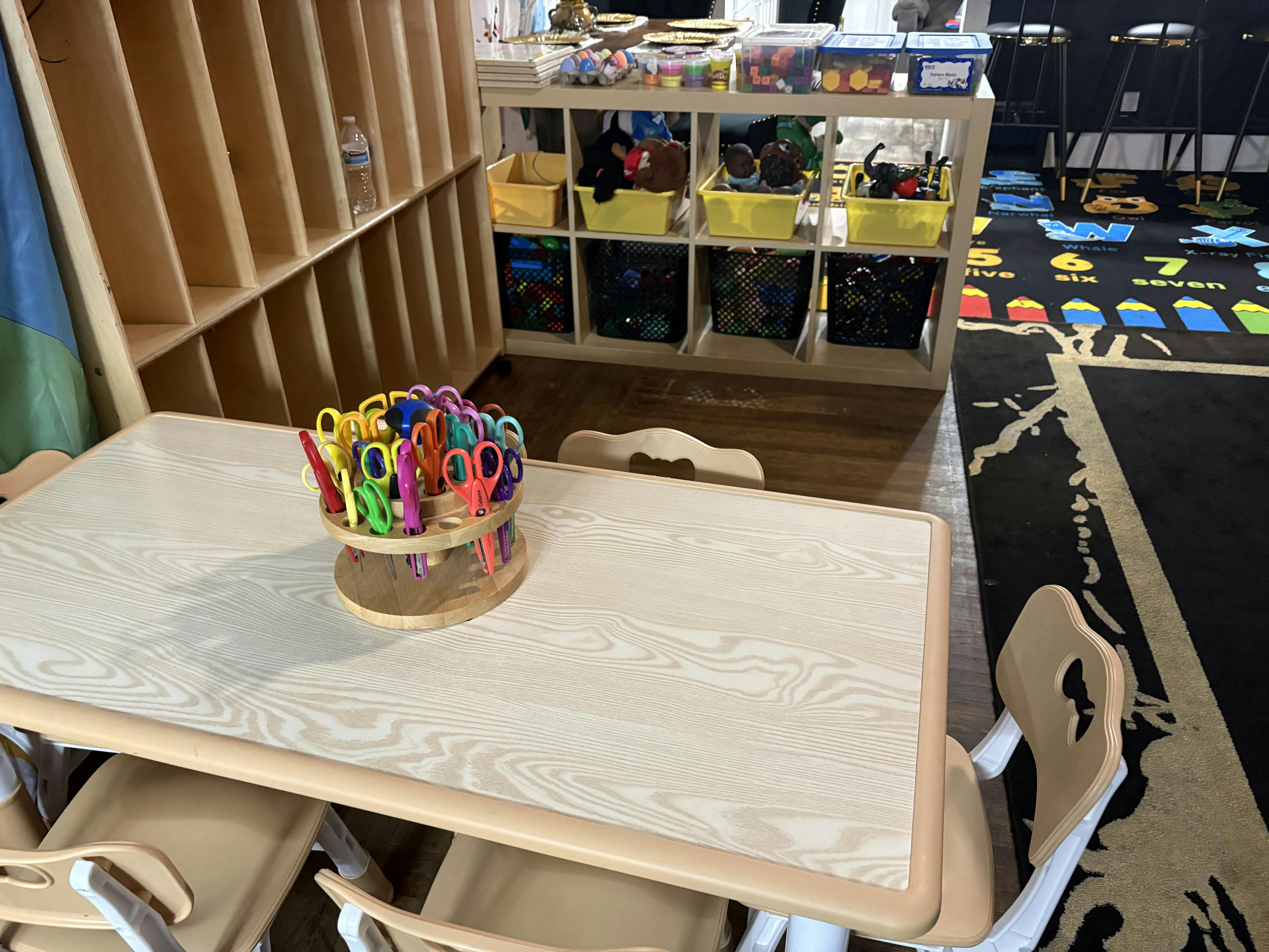 Wooden table with a carousel of children's scissors in a classroom