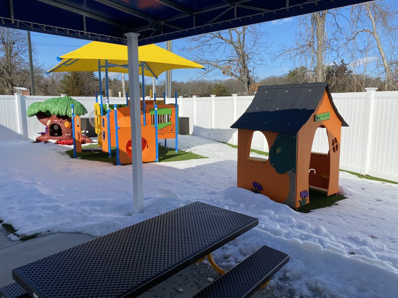 Playground with snow on the ground and a picnic table in the foreground