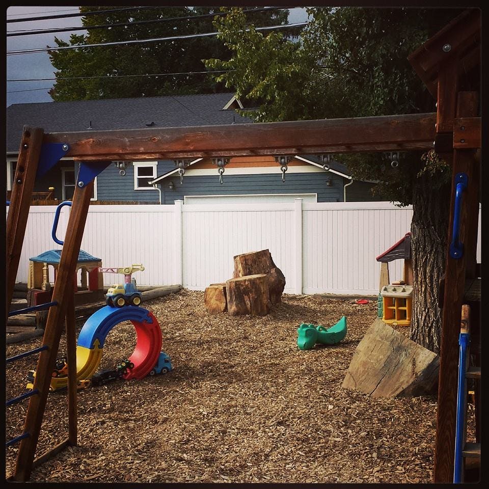 Playground with wood chips, swing set, and tree stumps