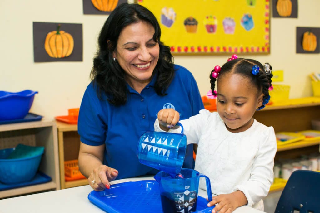 Adult and child pouring liquid from one blue container to another