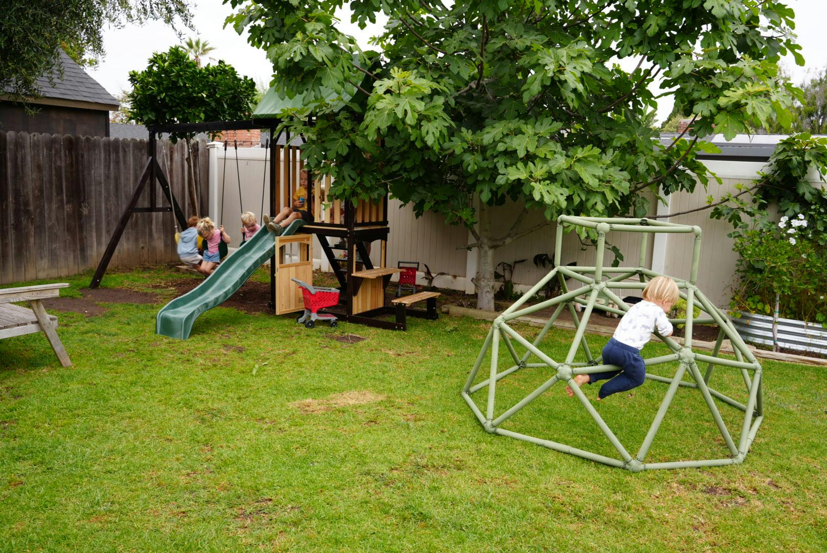 Children playing on a backyard swing set and a dome climber